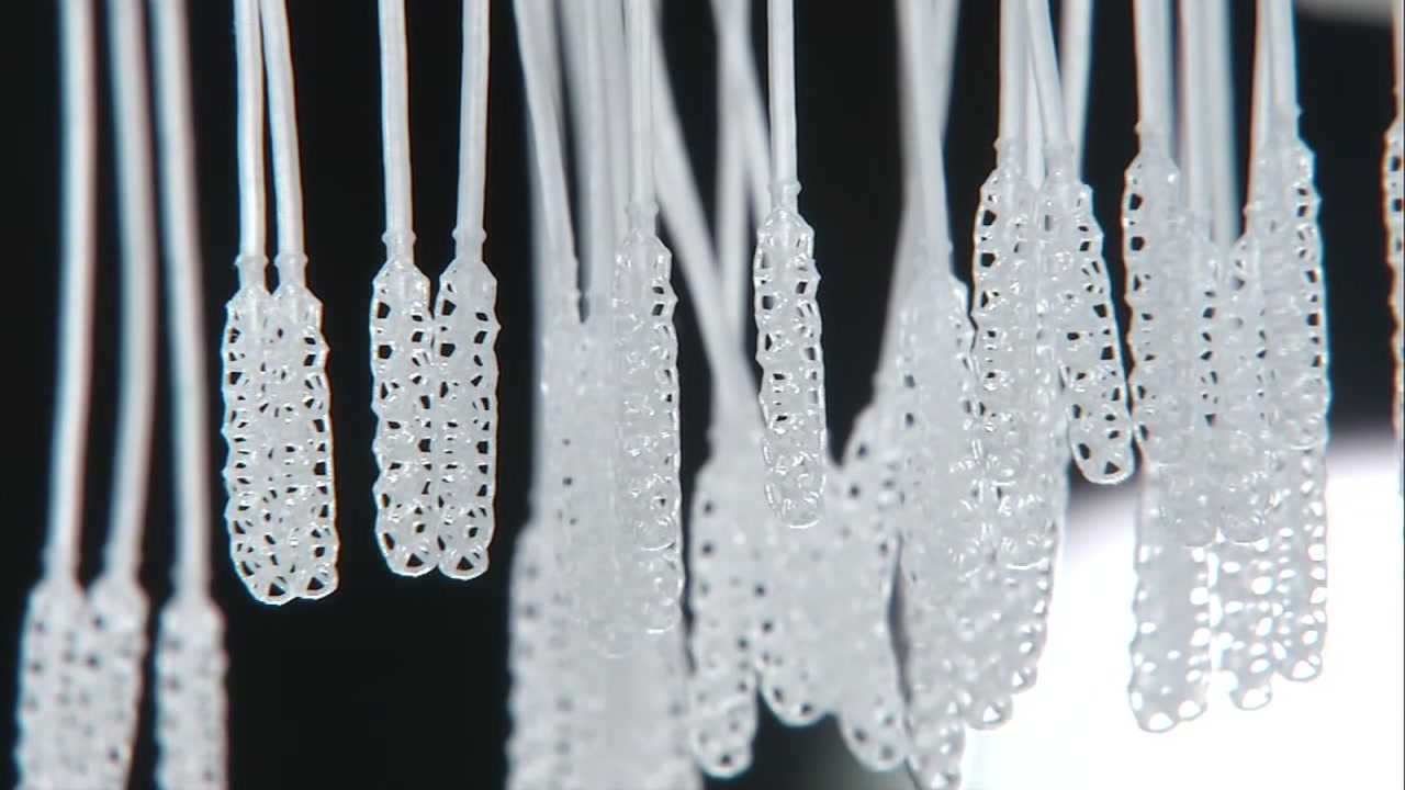 Close-up of translucent 3D-printed COVID-19 testing swabs hanging in rows